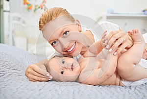 Mother hugging her baby lying on a bed