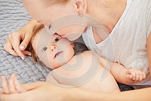 Mother hugging her baby lying on a bed