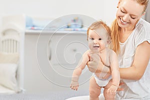 Mother hugging her baby lying on a bed