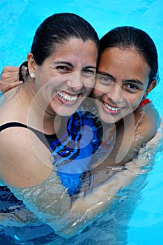 Mother hugging her daughter in the pool.