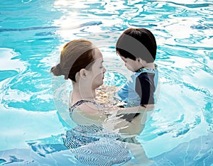 Mother hugging her son in the swimming pool at sunset : Soft fo