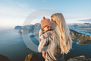 Mother hugging infant baby walking outdoor family lifestyle traveling in Norway summer vacations