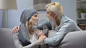 Mother hugging and kissing her hopeless daughter with cancer, family support