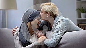 Mother hugging and kissing her hopeless daughter with cancer, family support