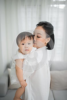 Mother hugging and kissing her little girl in living room, Kid at home