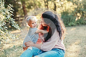 Mother hugging pacifying sad upset stressed crying toddler girl. Family young mom and crying baby in park outdoor. Bonding