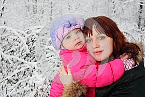 Mother hugs daughter in woods in snow