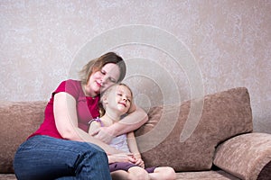 Mother hugs her daughter on couch