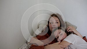 mother hugs her daughter lying on the bed