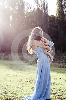 Mother hugs her little daughter in the rays of the setting sun