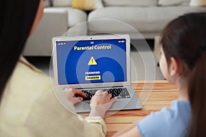 Mother installing parental control app on laptop to ensure her child`s safety at home, closeup