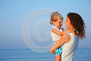 Mother keeps child at hands of edge of sea