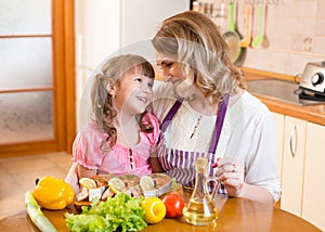 Mother and kid cook and communicate in kitchen