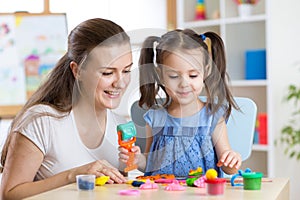 Mother and kid daughter at home molded from clay and play together. Concept of preschool or home education.