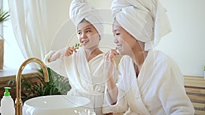Mother and kid girl brush teeth in bathroom together Spbd. Asian parent and daughter use eco wooden