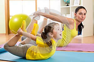 Mother and kid in the gym centre doing stretching fitness exercise. Yoga