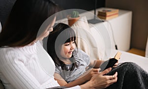 Mother and kid little girl reading a bedtime story together in bedroom.