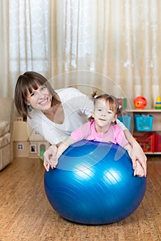 Mother and kid play with fitness ball indoors