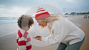 Mother kid playing seaside on autumn weekend. Beautiful woman holding stones