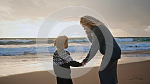 Mother kid resting shore on autumn sunset together. Smiling woman talking phone