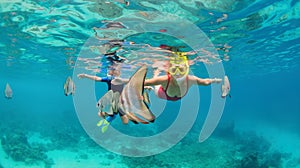 Mother, kid in snorkeling mask dive underwater with tropical fishes