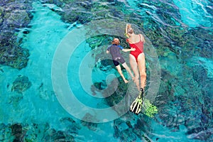 Mother, kid in snorkeling mask dive underwater with tropical fishes