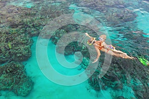 Mother, kid in snorkeling mask dive underwater with tropical fishes