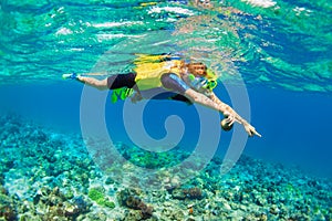 Mother, kid in snorkeling mask dive underwater with tropical fishes