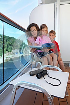 Mother, kids consider book on ship deck