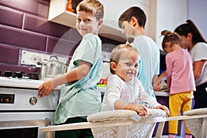 Mother with kids cooking at kitchen, happy children`s moments