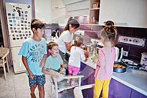 Mother with kids cooking at kitchen, happy children`s moments