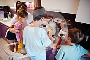 Mother with kids cooking at kitchen, happy children`s moments