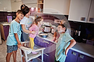 Mother with kids cooking at kitchen, happy children`s moments