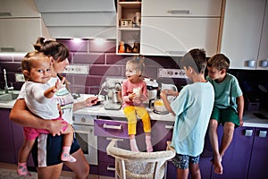 Mother with kids cooking at kitchen, happy children`s moments