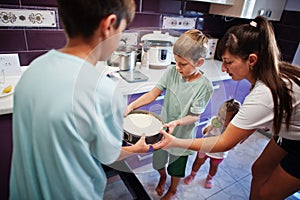 Mother with kids cooking at kitchen, happy children`s moments. Cheesecake in the oven