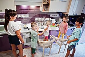 Mother with kids cooking at kitchen, happy children`s moments. Give high five each other