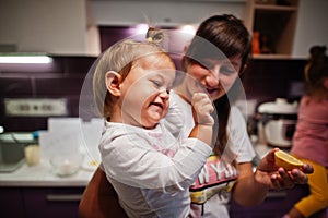 Mother with kids cooking at kitchen, happy children`s moments. Mom hold a lemon