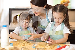 Mother and kids daughters weared aprons making cookies