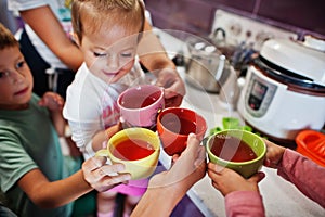 Mother with kids drink compote at kitchen, happy children`s moments