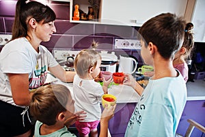 Mother with kids drink compote at kitchen, happy children`s moments