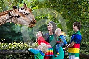 Mother and kids feeding giraffe at the zoo