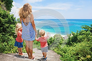 Mother, kids look at sea surf on white sand beach