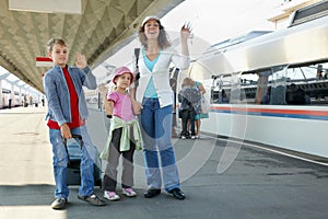 Mother with kids and luggage stands on platform