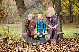 Mother with kids twins sit at bench