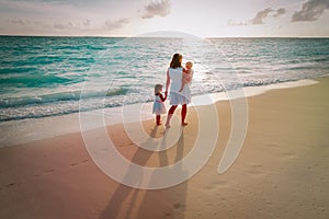 Mother and kids walking on beach leaving footprint in sand