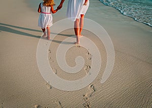 Mother and kids walking on beach leaving footprint in sand