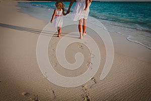 Mother and kids walking on beach leaving footprint in sand