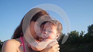 Mother kisses baby against blue sky.