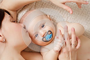 a mother kisses the baby on the bed. maternal and child health.