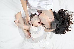 Mother kisses baby lying on the bed closeup